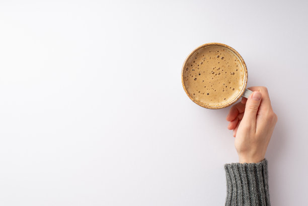 秋天的概念。第一人称俯视图照片的女性手在灰色套头衫拿着一杯泡沫咖啡在孤立的白色背景与空白图片下载