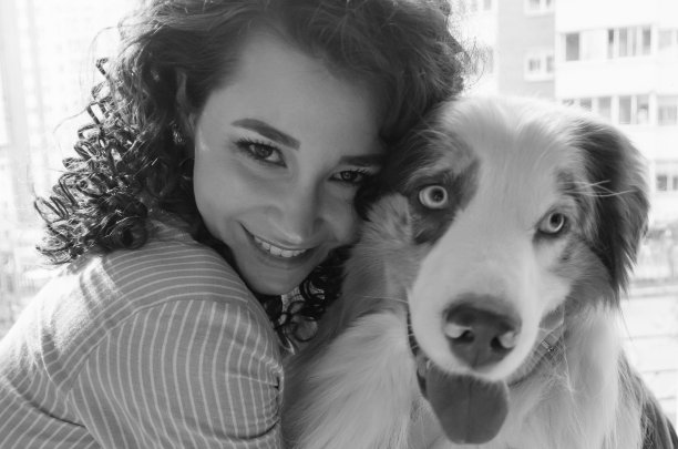 美丽的女人和她的狗一起摆姿势，澳大利亚牧羊犬和年轻的卷毛女人，宠物和休闲的概念图片下载