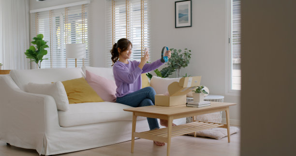 年轻的亚洲人快乐的少女影响者微笑开盒子打开礼品盒享受购买订单网上商店商店照片拍摄相机展示张贴社交媒体应用程序博客视频博客分享坐在家里放松沙发沙发。图片下载