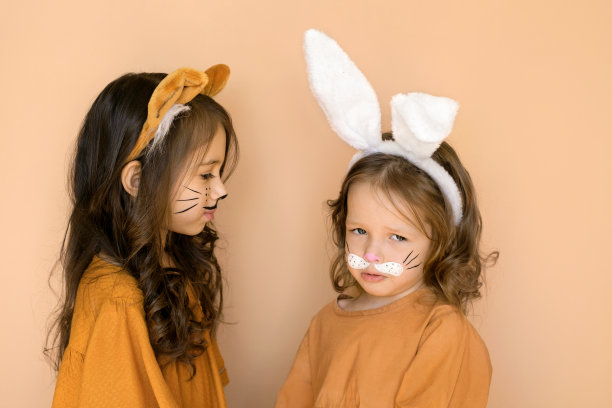 一个被冒犯的、心烦意乱的孩子化着兔子的妆，一个女孩扮成老虎的样子。用耳朵的帽子图片下载