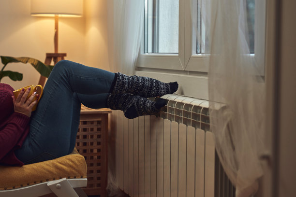 女人在寒冷的冬天给脚取暖，拿着咖啡茶杯，能源和天然气危机，寒冷的房间，供暖问题。图片下载