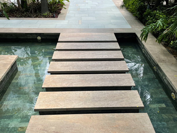 矩形的台阶跨过正式的特写图像，瓷砖花园池塘，铺就的路径，花坛灌木，水的反射，关注前景图片下载