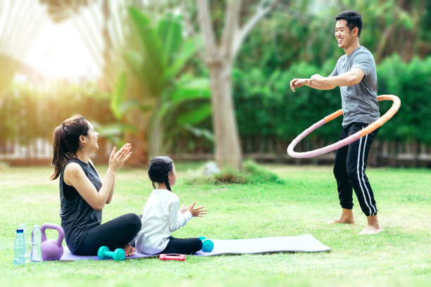 快乐的亚洲家庭在花园里，父亲，母亲和女儿。他们在家里的花园里玩呼啦圈玩得很开心图片下载