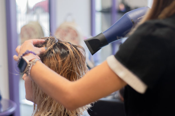 理发师用吹风机吹女人的头发。图片下载