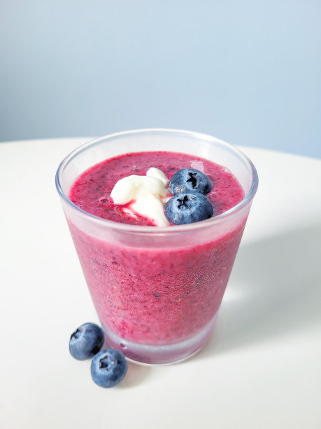 蓝莓酸奶冰沙，白色桌子，蓝色背景图片下载