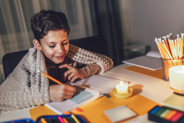 小男孩拿着燃烧的蜡烛学习。图片下载