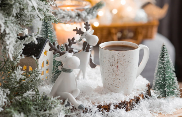 一张有可爱驯鹿的圣诞卡和一杯以美丽的焦景为背景的热咖啡。新年静物画。家庭度假的概念，温馨和舒适。图片下载