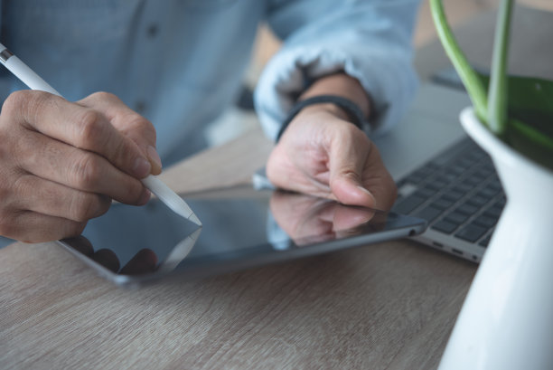 近距离的商务人员使用电子笔或手写笔在数字平板电脑上签署电子文件，在工作场所的笔记本电脑上在线工作图片下载