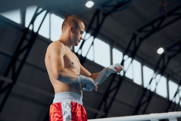 在室内的体育馆里，男拳击手在比赛前裹住双手。年轻运动员准备打架的特写镜头。体育的概念。素材图片