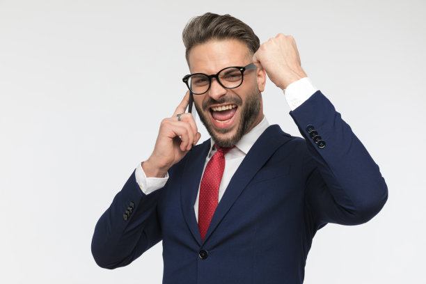 热情的戴眼镜的年轻人一边打电话一边庆祝图片下载