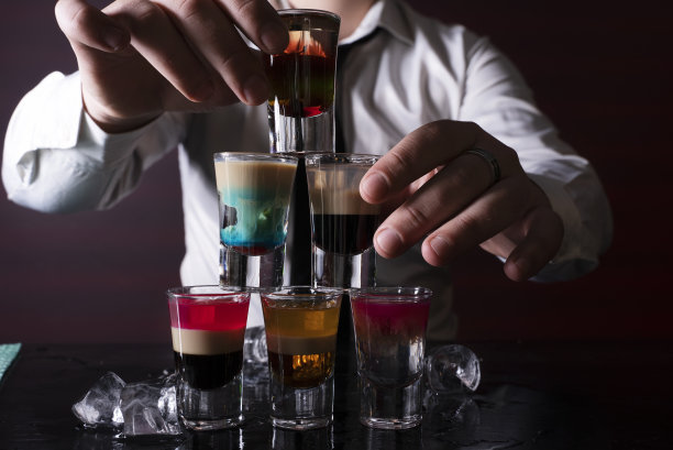 调酒师将烈性酒精饮料倒入吧台上的小玻璃杯中图片下载