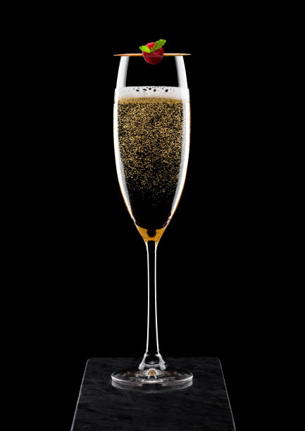 优雅的玻璃黄色香槟与rasspbery棍子在黑色大理石板上黑色背景。图片下载