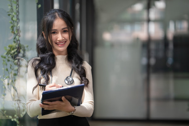 一位年轻的女医生站在医院里用写字板工作图片下载