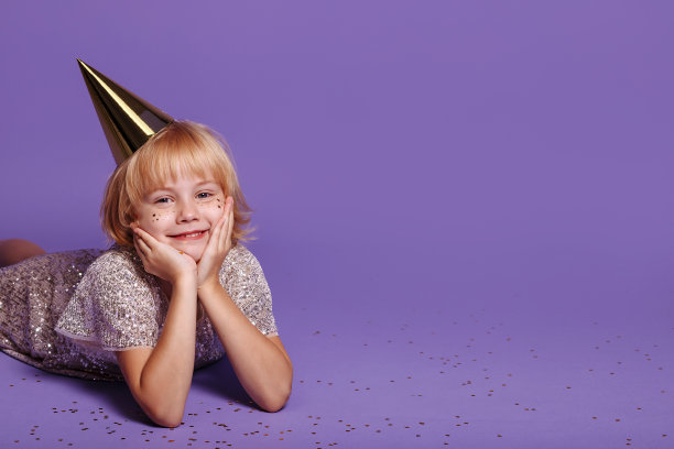 紫色背景上戴节日帽的孩子。图片下载