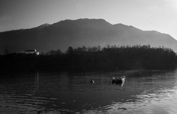 科摩湖上的田园风光(有一点雾)，有一艘有盖的船，有一个岛和一个岛(isola)远处的科马奇诺(无法辨认的人)图片下载