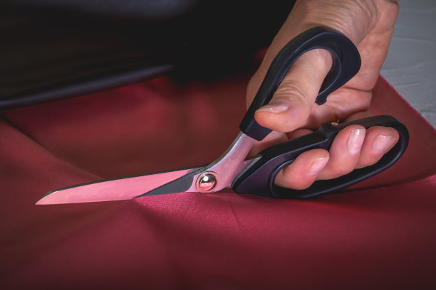 裁缝的剪刀在一个女人的手里剪布料。特写镜头图片下载