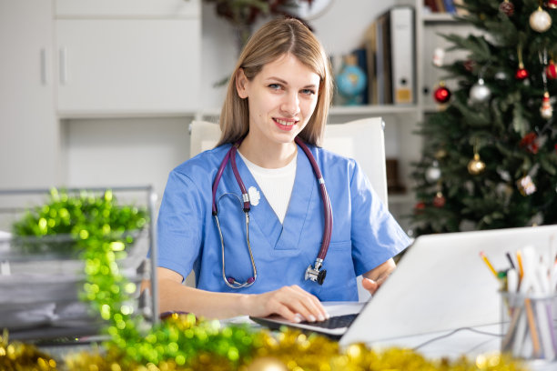 积极的女医生在医务室工作，圣诞节期间使用笔记本电脑图片下载