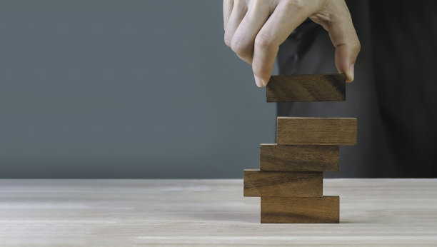 手工安排木块堆叠在顶部，白色背景。经营理念为成长成功的过程图片下载
