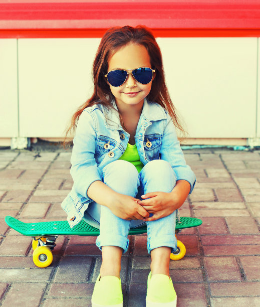 在城市街道上玩滑板的小女孩的画像图片下载
