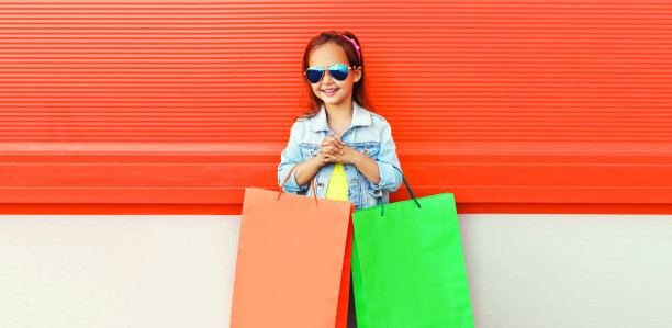 肖像小女孩与购物袋在城市街道上橙色图片下载