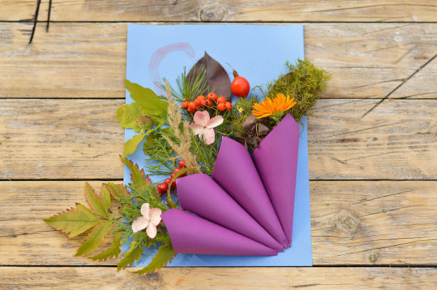 木桌上静物画的秋季应用。孩子们从纸伞上剪下来，用树叶、花朵、浆果等天然材料装饰。图片下载