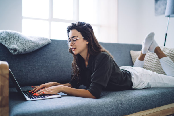 美丽的白人女性戴着眼镜矫正视力，在笔记本电脑上打字，在博客上分享出版物，熟练的职业女性自由职业者远程工作在现代家庭内部图片下载