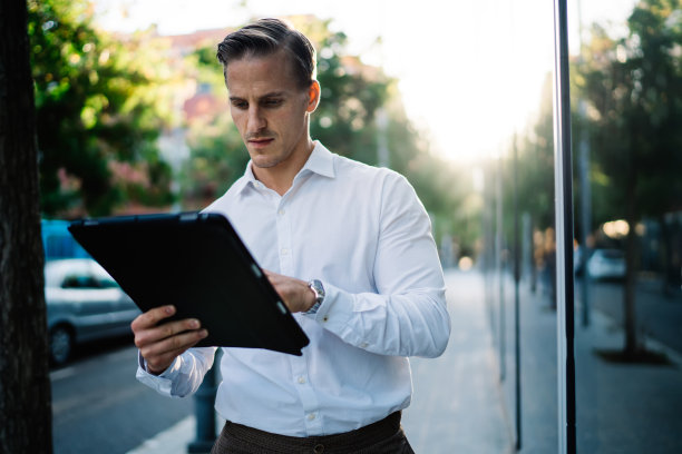 年轻的白人商人在市中心使用4g网络连接，通过现代触摸板检查银行交易，千禧一代企业家站在街道上阅读网络出版物图片下载