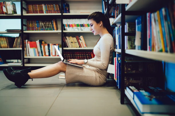 聪明的女人在图书馆用笔记本电脑工作图片下载