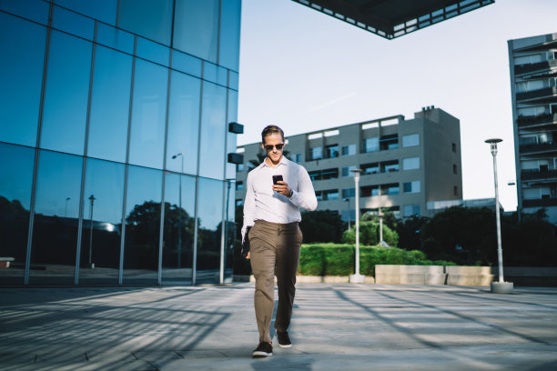 穿着时髦的年轻商人通过智能手机平台进行网上银行预订，英俊的男经理用手机连接无线上网搜索财经新闻图片下载