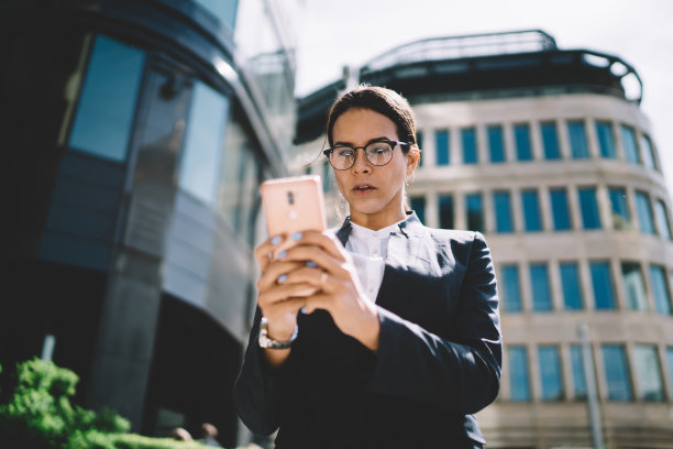 惊讶的女子在城市里用手机冲浪图片下载