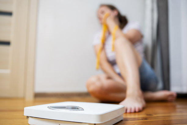 白色的刻度和沮丧，不安和悲伤的女人用卷尺在木地板上图片下载