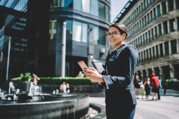 快乐的女人在商业区使用智能手机图片下载