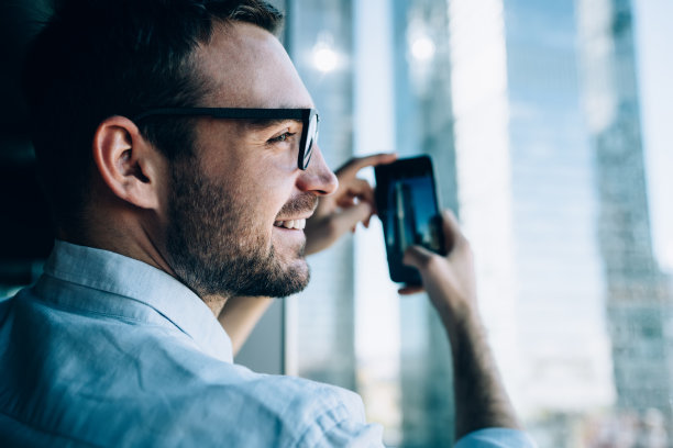 近距离观察愉快的男雇主在光学眼镜拍摄视图在工作日，快乐的商人使用手机相机通过移动医疗应用程序点击图片图片下载