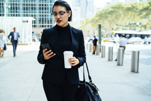 自信的年轻女士在街上使用智能手机图片下载