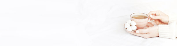 穿着白色针织衫的女子手捧一杯热茶，茶碟上放着精致的棉花。舒适的早餐在家里。生活方式温和背景复制空间秋冬概念图片下载