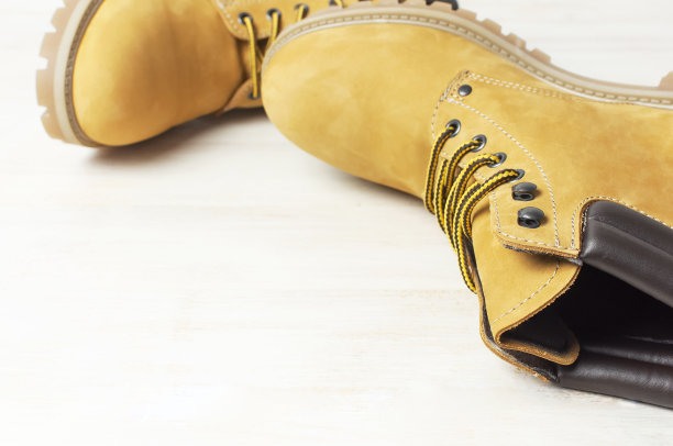 特写黄色男人的工作靴从天然磨砂皮在木制白色背景。时尚休闲鞋的青春风格。秋冬鞋销售店广告概念图片下载