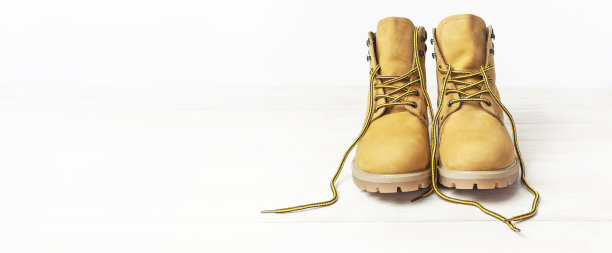 黄色男人的工作靴由天然磨砂皮在木制白色背景。时尚休闲鞋，青春风。秋冬鞋子广告概念、销售、店铺图片下载