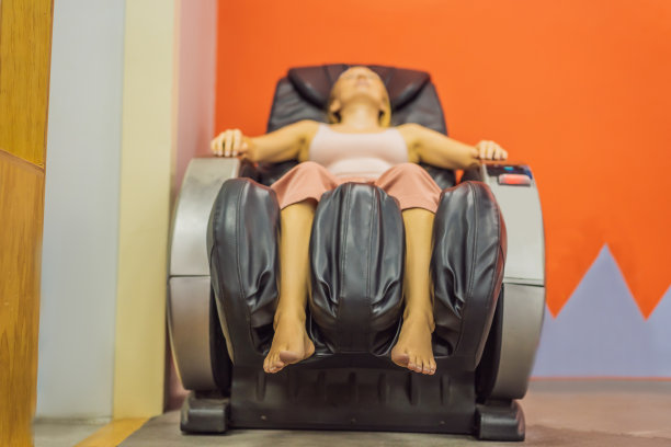 美丽的年轻女子在机场或商场的按摩椅上放松图片下载