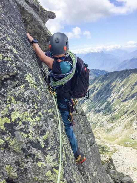 清晨，男人爬上阳光明媚的岩壁图片下载