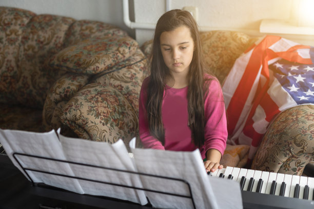 小女孩在家里用美国国旗弹奏合成器钢琴图片下载