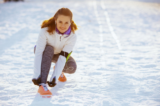 微笑的年轻女子在白色夹克系你的鞋带图片下载