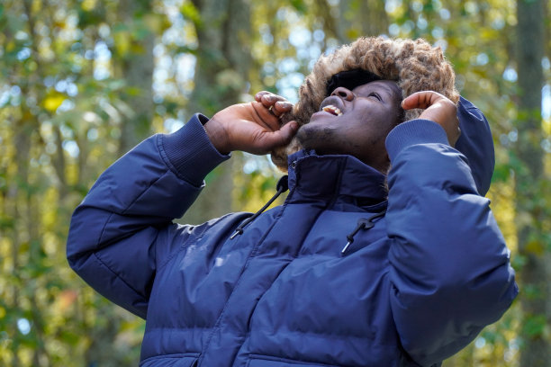 穿冬衣带兜帽的黑人抬头看。冬季时尚。图片下载