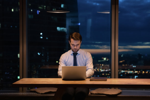 专注的男员工在深夜用笔记本电脑开发项目图片下载