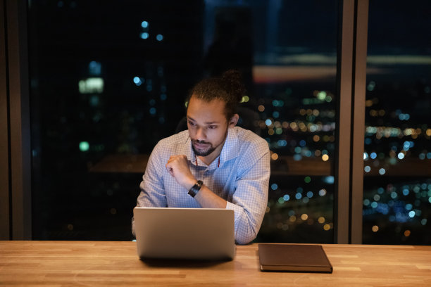 混血男性员工下班后在办公室研究电子文档图片下载