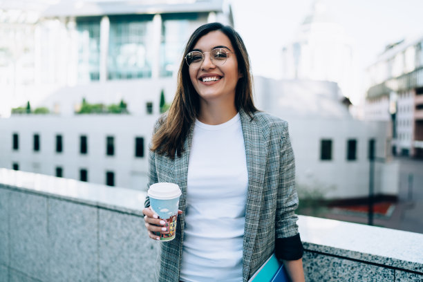 半幅肖像的快乐快乐的白人妇女满足咖啡休息，拿着杯子，笑在街上，微笑着穿着时髦的商务妇女享受一天在城市看相机图片下载