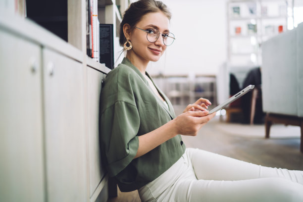 快乐的女人一边用平板电脑一边看相机图片下载