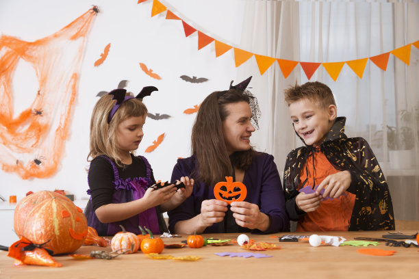 妈妈和两个孩子穿着化装舞会的服装为万圣节做装饰和工艺品图片下载