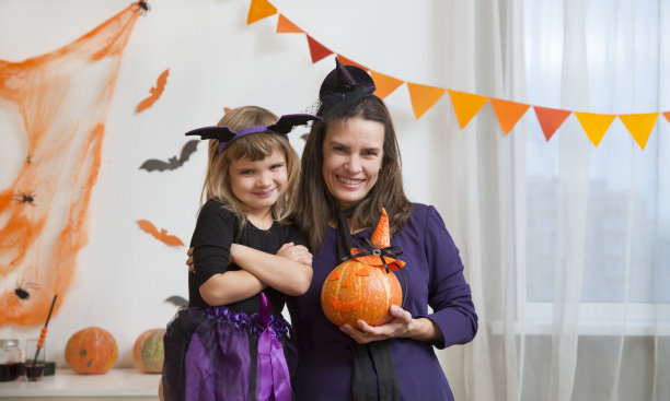 快乐的妈妈和孩子女孩的女儿
穿着女巫服装万圣节不给糖就捣蛋家里喜庆的秋季节日装饰。图片下载
