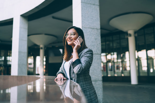 积极的年轻女性千禧一代学生站在城市环境中用手机通话，微笑的白人潮女孩用智能手机交谈，满意的良好漫游费用图片下载