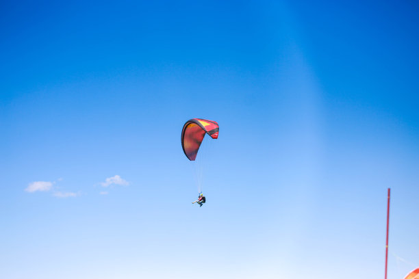 一个年轻人在晴朗多云的天气里滑翔伞图片下载